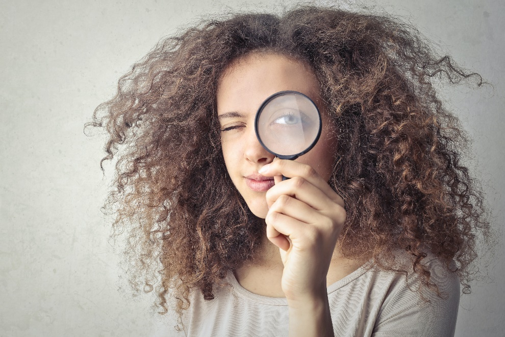 Woman looking through a magnifying glass